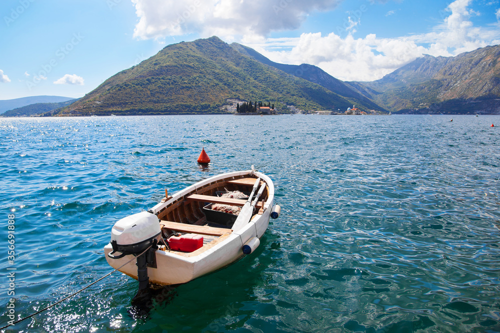 fishing boat on blue adriatic waters with mountains in the background in Perast, Montengro; Kotor Bay area