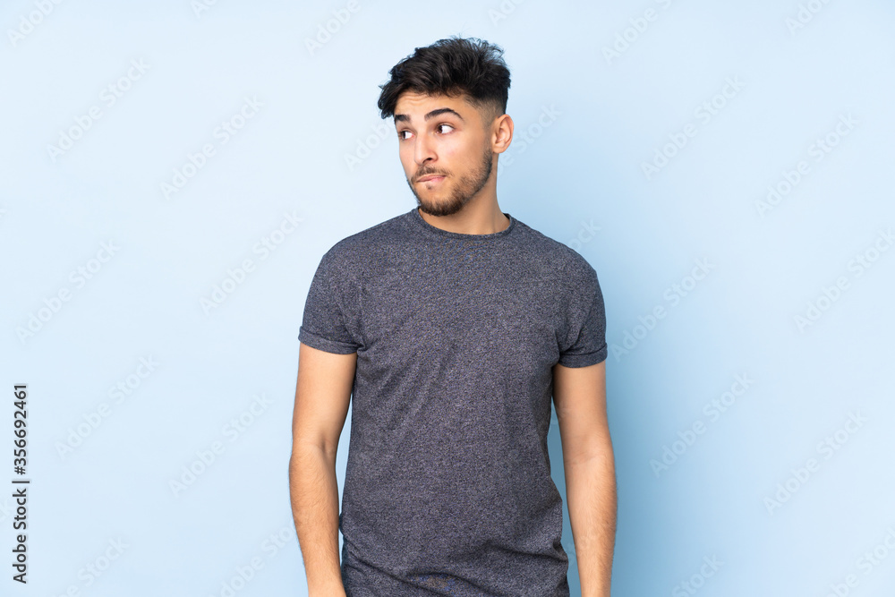 Arabian handsome man over isolated background having doubts while looking up Arabian handsome man over isolated background having doubts while looking up