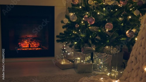 Christmas celebration in cozy interior with decorated firr tree, fireplace and merino plaid. Evening time. Winter holidays photo