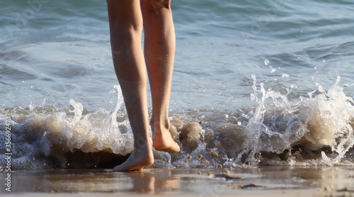 Feet of a girl walking on the seashore.