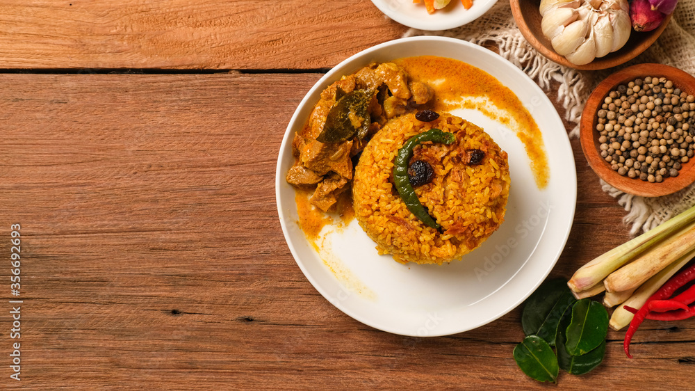 Indian Mutton Biryani Dish served on wooden table. Typical food from India, made from goat meat mixed with spices and basmati rice