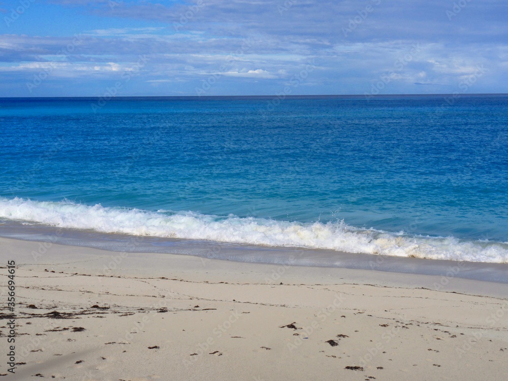 Waves break against the soft white sand in a tropical beach Waves break against the soft white sand in a tropical beach