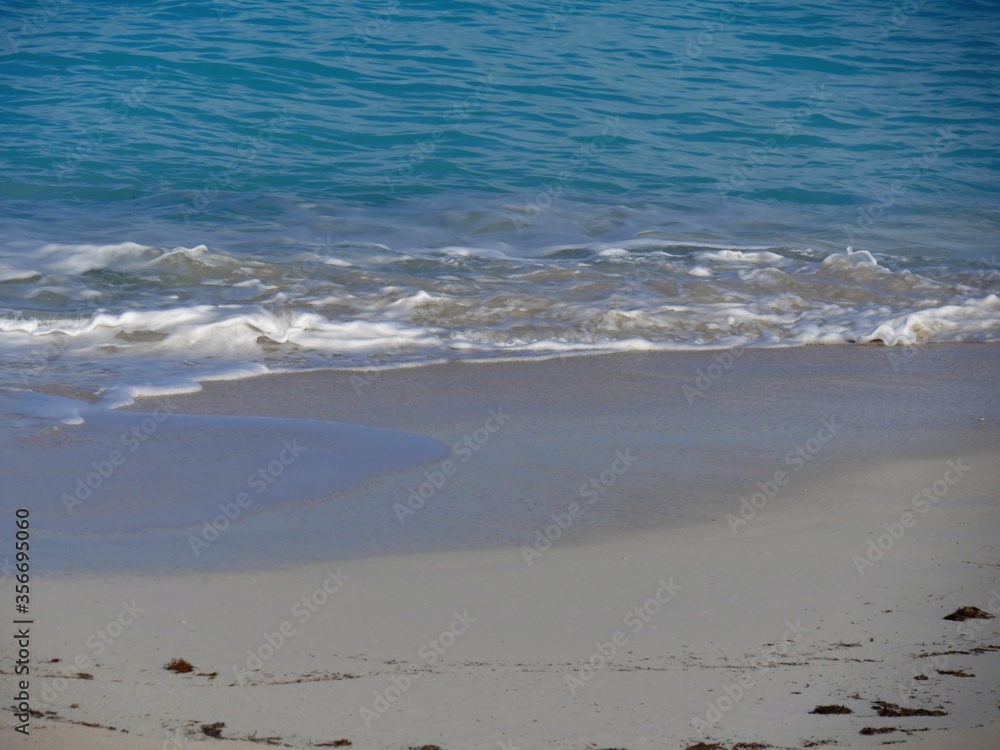 Soft gentle waves break into the fine white sands in a tropical beach Soft gentle waves break into the fine white sands in a tropical beach