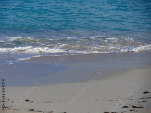 Soft gentle waves break into the fine white sands in a tropical beach