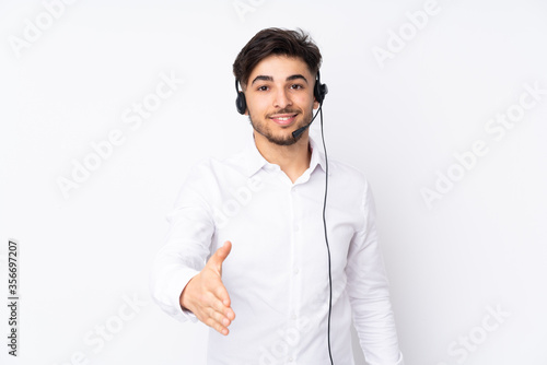 Telemarketer Arabian man working with a headset isolated on white background handshaking after good deal © luismolinero