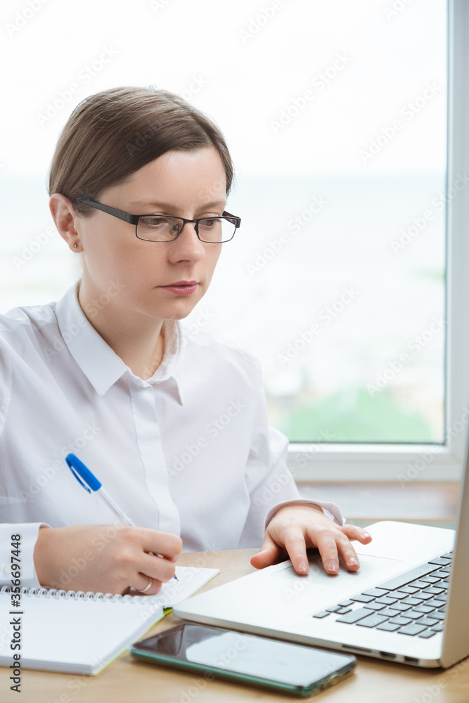 Young woman doing notes and working on laptop. Deadline coming. Young woman doing notes and working on laptop. Deadline coming.
