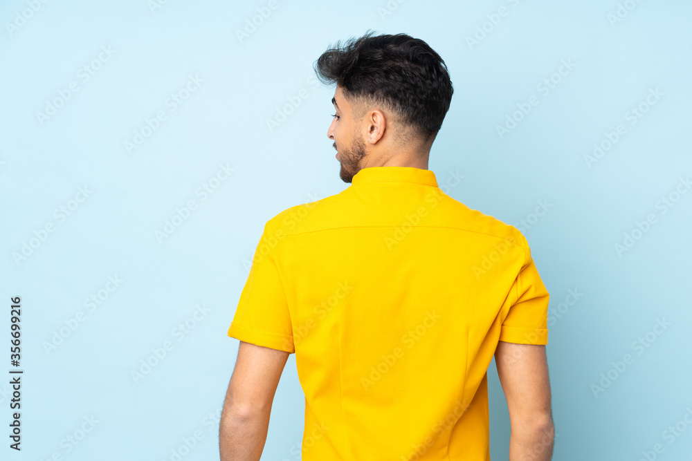 Arabian handsome man over isolated background in back position and looking side Arabian handsome man over isolated background in back position and looking side