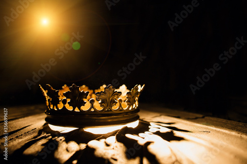 Fotografie The crown on a black background is illuminated by a golden beam