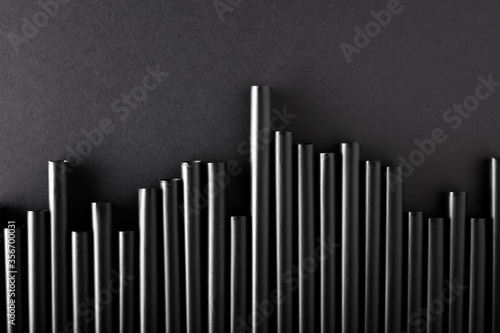 Black plastic cocktail straws arranged as fluctuating graph chart