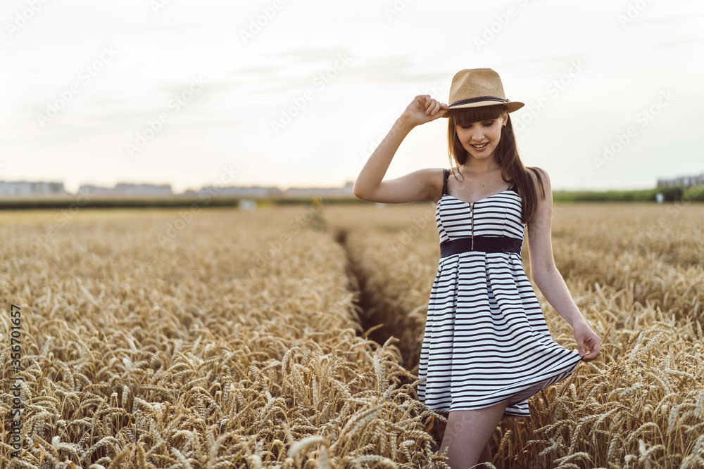 Pretty brunette girl in light dress walking outdoor in wheat field