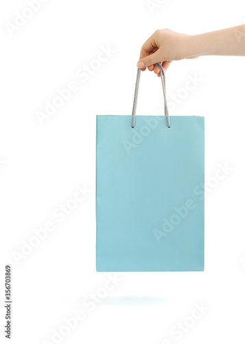 Blue paper bag for shopping in hand. Isolated on white background.