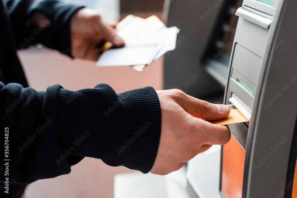Cropped view of thief holding credit cards while using automated teller machine Cropped view of thief holding credit cards while using automated teller machine