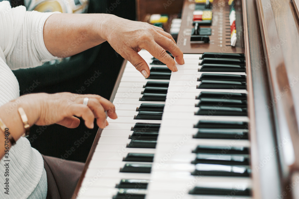 Fototapeta premium Close up elderly grandmother hand playing piano in living room at home, old woman activity lifestyle after retirement , living quality and insurance concept
