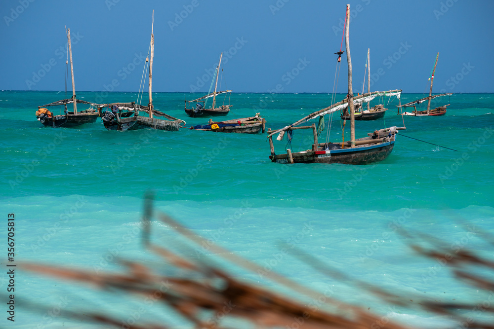 Obraz premium Anchored Traditional wooden dhow boats on the amazing turquoise water in the Indian ocean at Nungwi village, Zanzibar, Tanzania