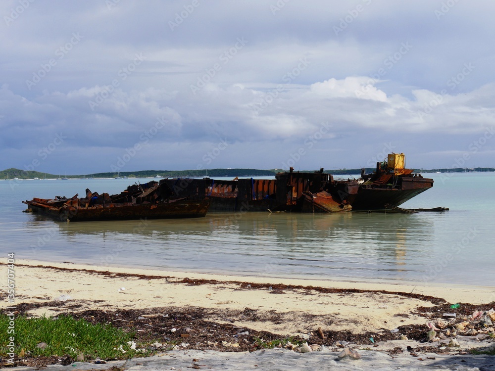 Rusty scraps from a shipwrecked fishing boat is docked by the shores of a white sand beach in George Town, Bahamas Rusty scraps from a shipwrecked fishing boat is docked by the shores of a white sand beach in George Town, Bahamas