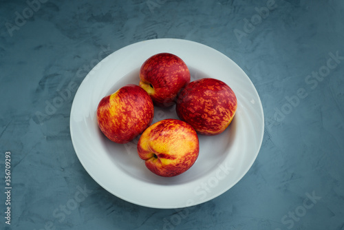 A plate of peaches on a blue concrete table. Top view of fruits.