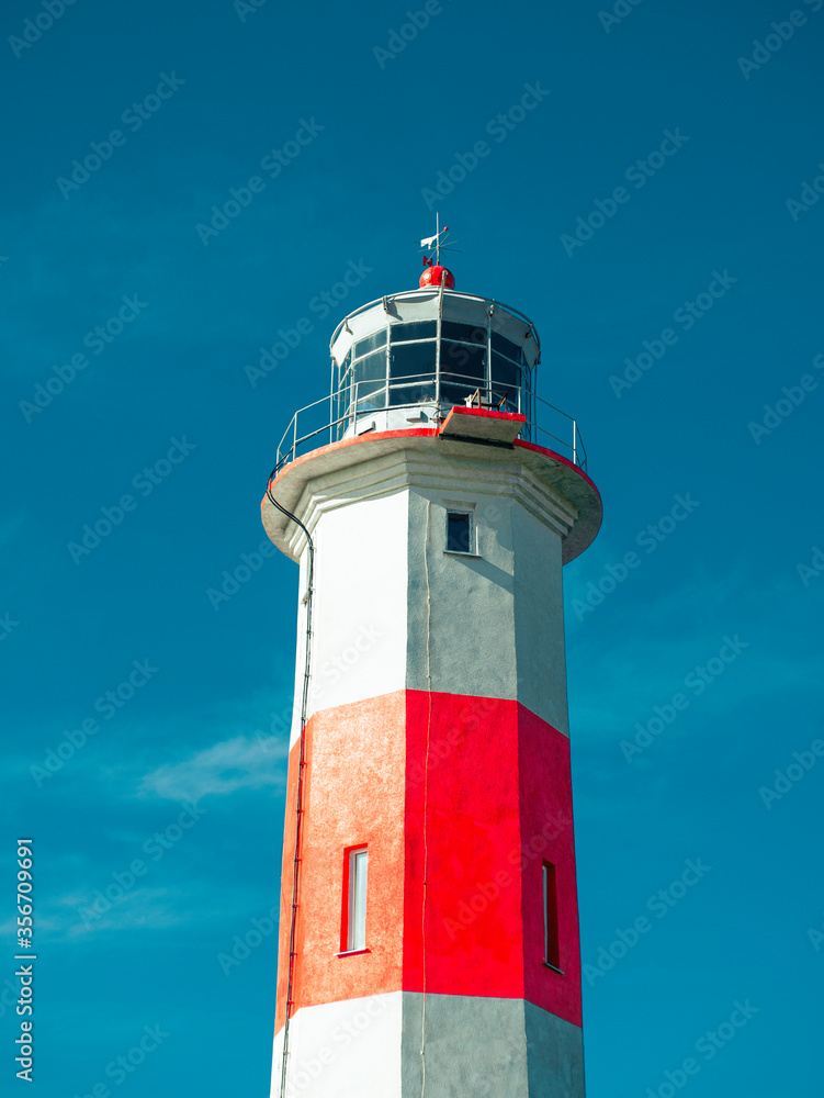 Beautiful old lighthouse, red white, isolated on blue sky background. Beautiful old lighthouse, red white, isolated on blue sky background.