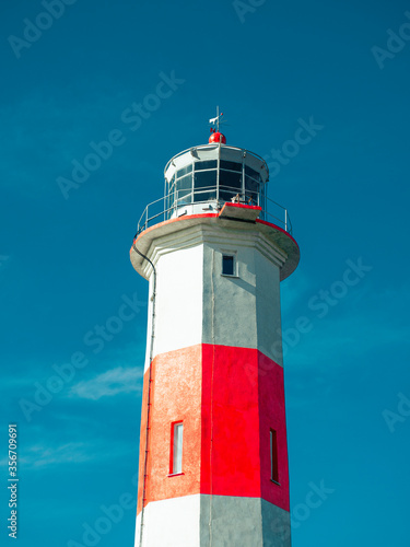 Beautiful old lighthouse, red white, isolated on blue sky background.