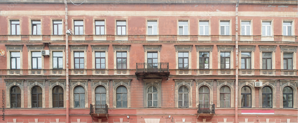Facade of an old residential building with stucco on the wall. Panorama.