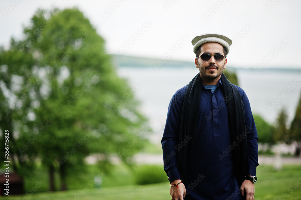 Stylish pakistani indian muslim arabic man in kurta dhoti suit, traditional pakol hat and sunglasses.
