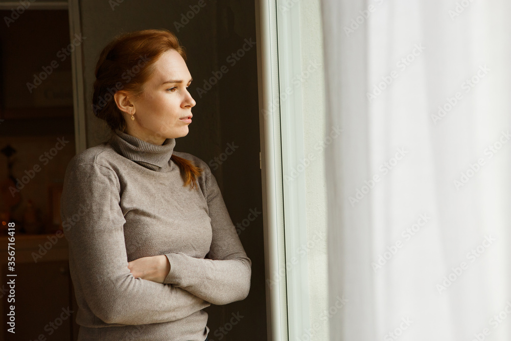 sad girl standing at window and looks into distance. upset woman waiting someone sad girl standing at window and looks into distance. upset woman waiting someone