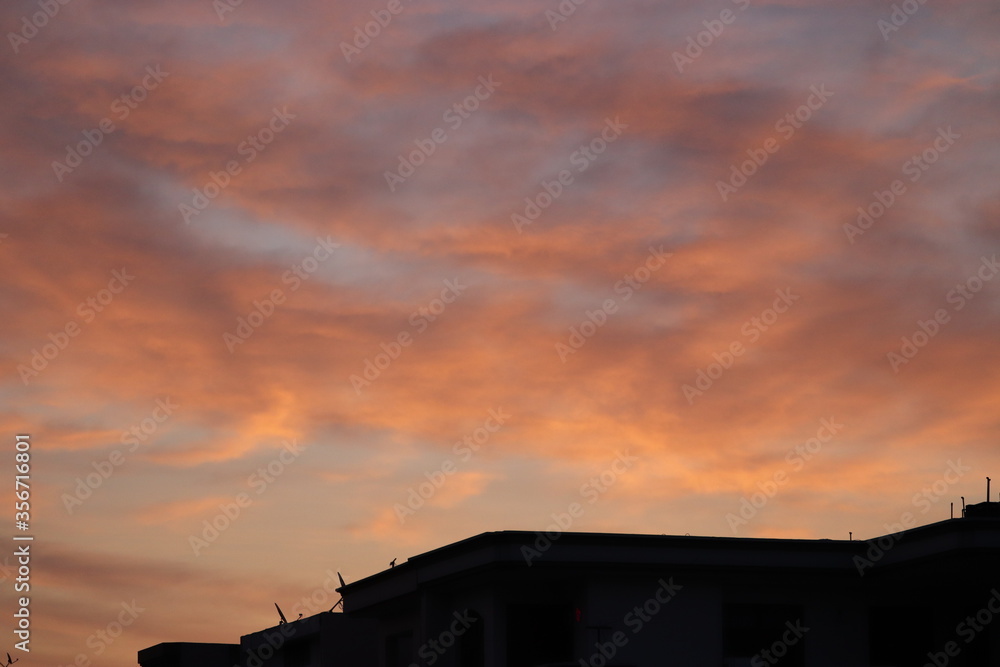 Amber Clouds over silhouetted rooftops in the morning sky