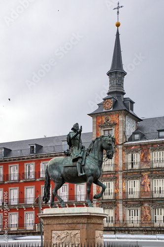 Bronze statue of King Philip III at the center of Plaza Mayor, a major public space in the heart of Madrid, Casa de la Panaderia (Bakery House) on background.