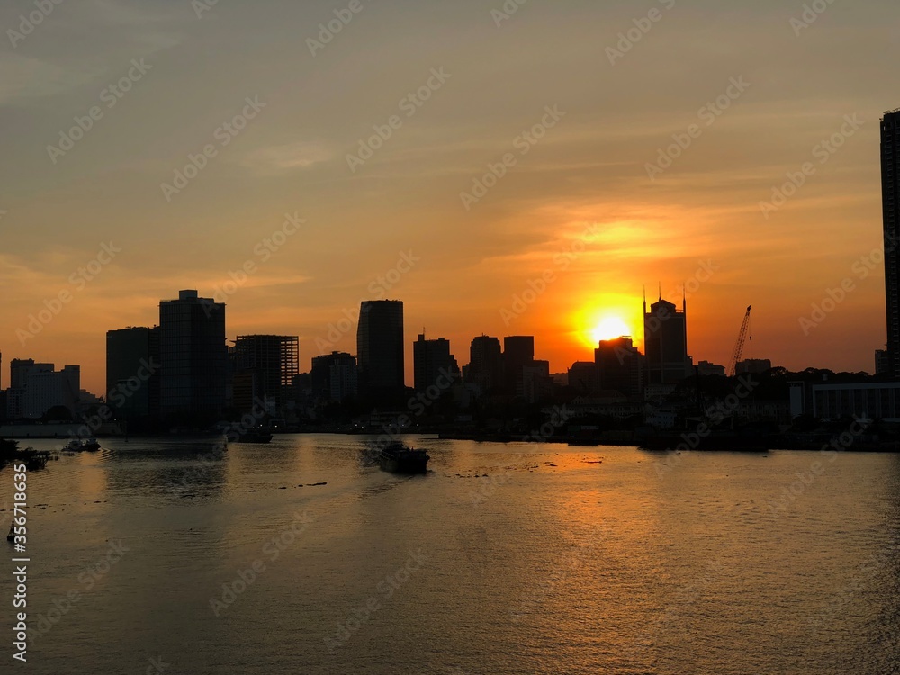 Silhouettes of buildings outlined in the sunset over the Mekong Delta river in Vietnam.