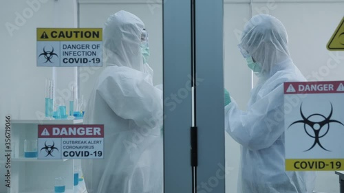 Two asian scientist is wearing Personal Protective Equipment (PPE) in laboratory. Slow motion Dolly slider shot