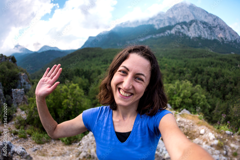 A woman takes a selfie on top of a mountain.