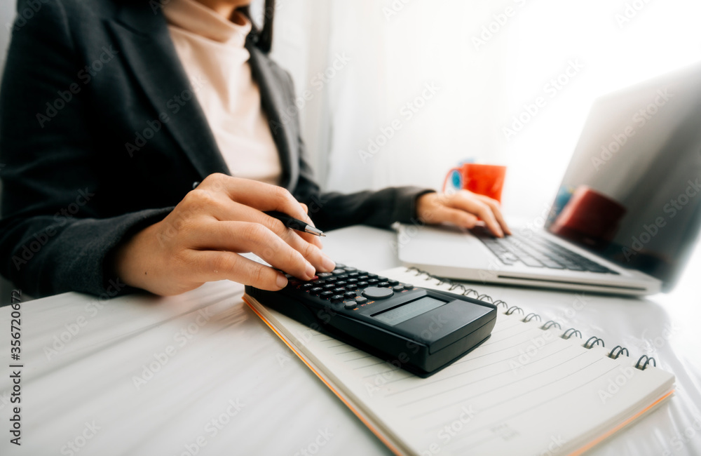 business hand working with finances about cost and calculator and laptop with tablet on withe desk at office in morning light business hand working with finances about cost and calculator and laptop with tablet on withe desk at office in morning light