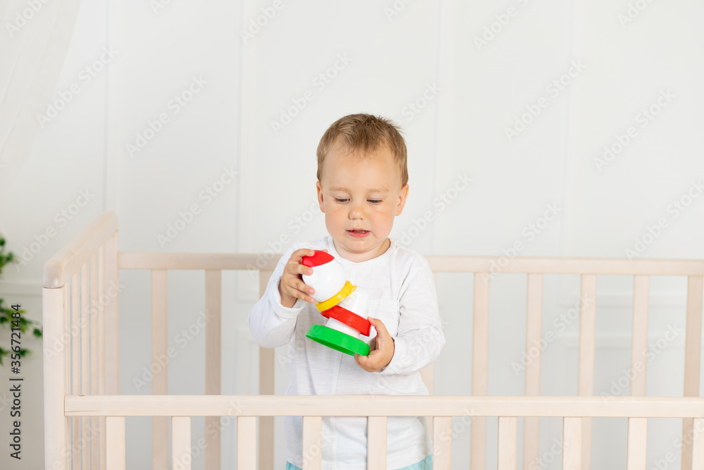Four months old little boy playing in baby bed. Toys are officially property released