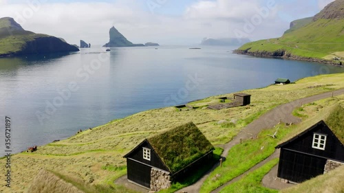4k drone footage (Ultra High Definition) of Bour village with typical turf-top houses and Tindholmur cliffs on background. Beautiful morning view of Vagar island, Faroe, Denmark, Europe. 