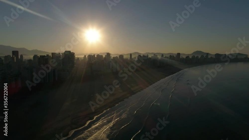 Drone shot Santos Brazil beach and buildings on sunrise with youth parting on the hill
 photo