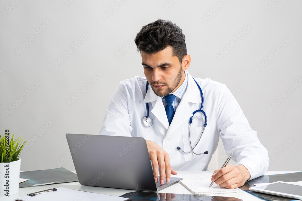 Handsome doctor sitting at desk in office
