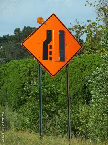 Road sign warning drivers that the lane will end and merge. This is usually posted on the road where construction or road repair is in progress. photo