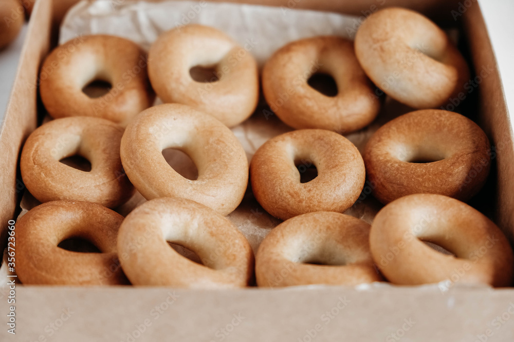 Drying or round bagels in a paper box on a white wooden background. Top view. Copy, empty space for text Drying or round bagels in a paper box on a white wooden background. Top view. Copy, empty space for text