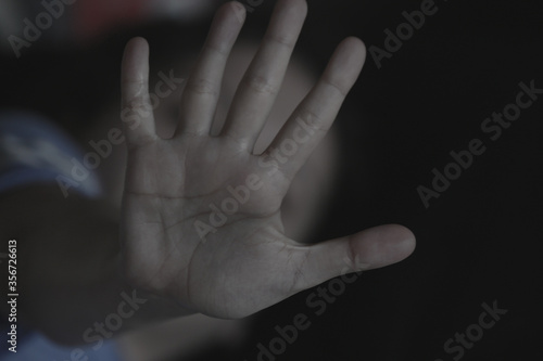 The palm of a female hand giving the signal to stop. The dark, moody image is a concept of a woman being abused, raped, beaten, threatened, robbed, domestic violence etc. A sign of the  metoo movement © Thomas