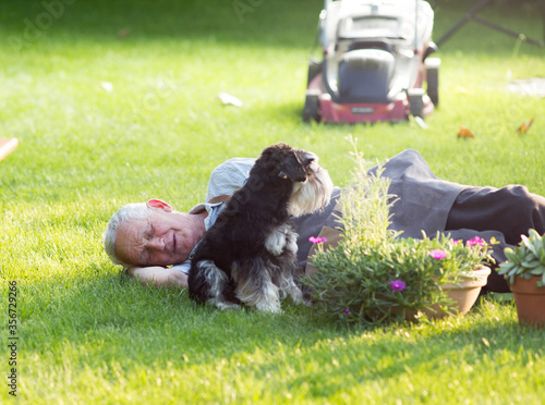 Senior man with dog resting on lawn
