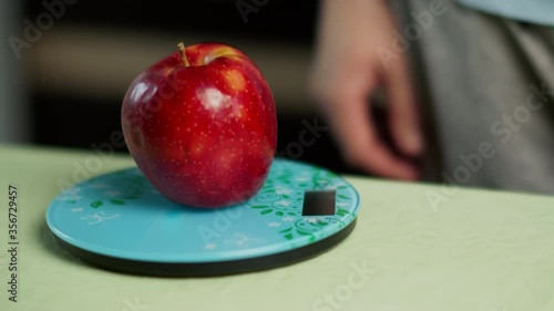 Wallpaper Mural A man weighs a fresh red apple on a kitchen scale, close-up Torontodigital.ca