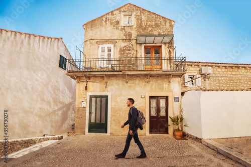 Young man walking on the background of old houses photo