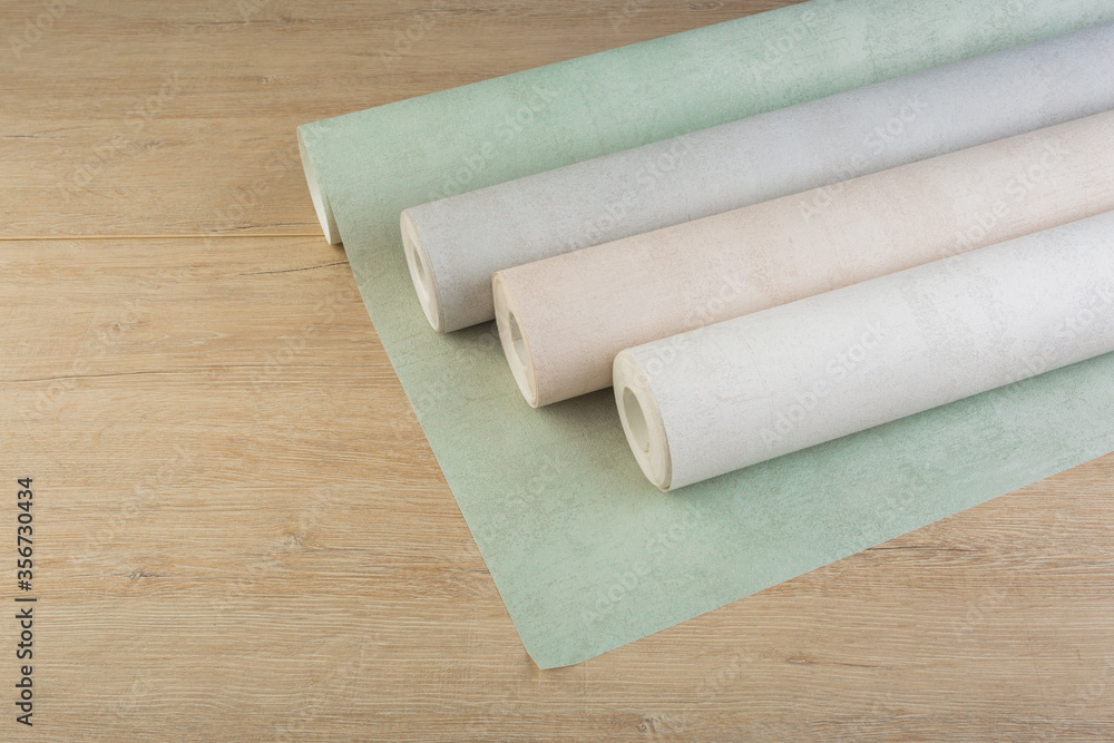 rolls of multi-colored paper wallpaper on a wooden table rolls of multi-colored paper wallpaper on a wooden table