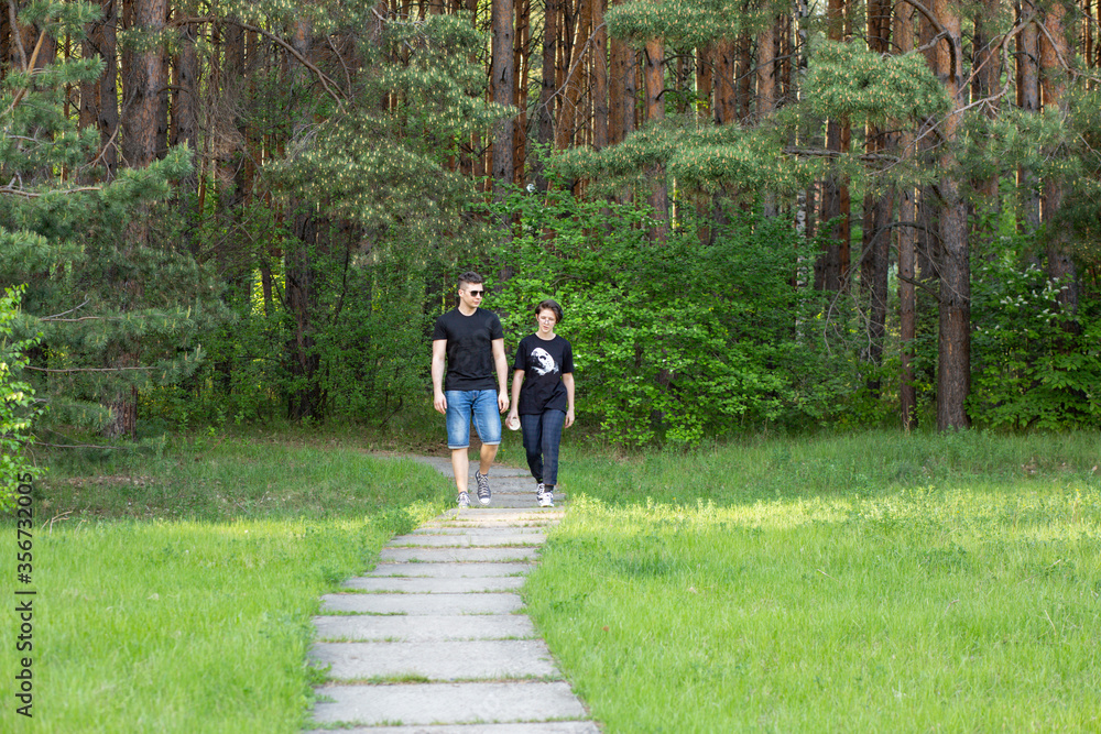 Fototapeta premium A pair of young people walks in the park among beautiful nature