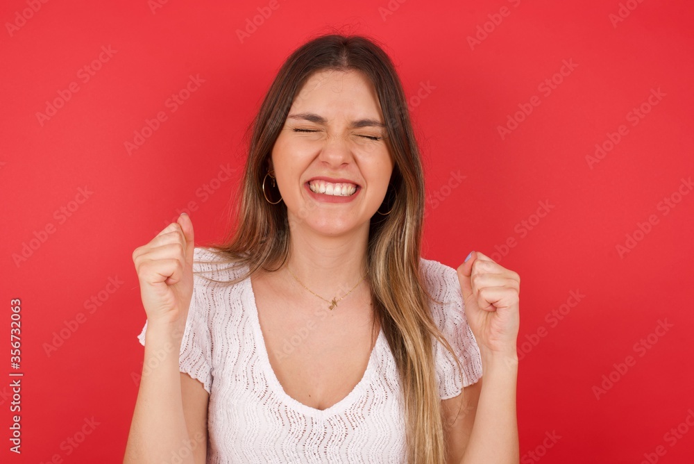 Caucasian brunette woman rejoicing her success and victory clenching her fists with joy. Lucky woman being happy to achieve her aim and goals. Positive emotions, feelings. Caucasian brunette woman rejoicing her success and victory clenching her fists with joy. Lucky woman being happy to achieve her aim and goals. Positive emotions, feelings.