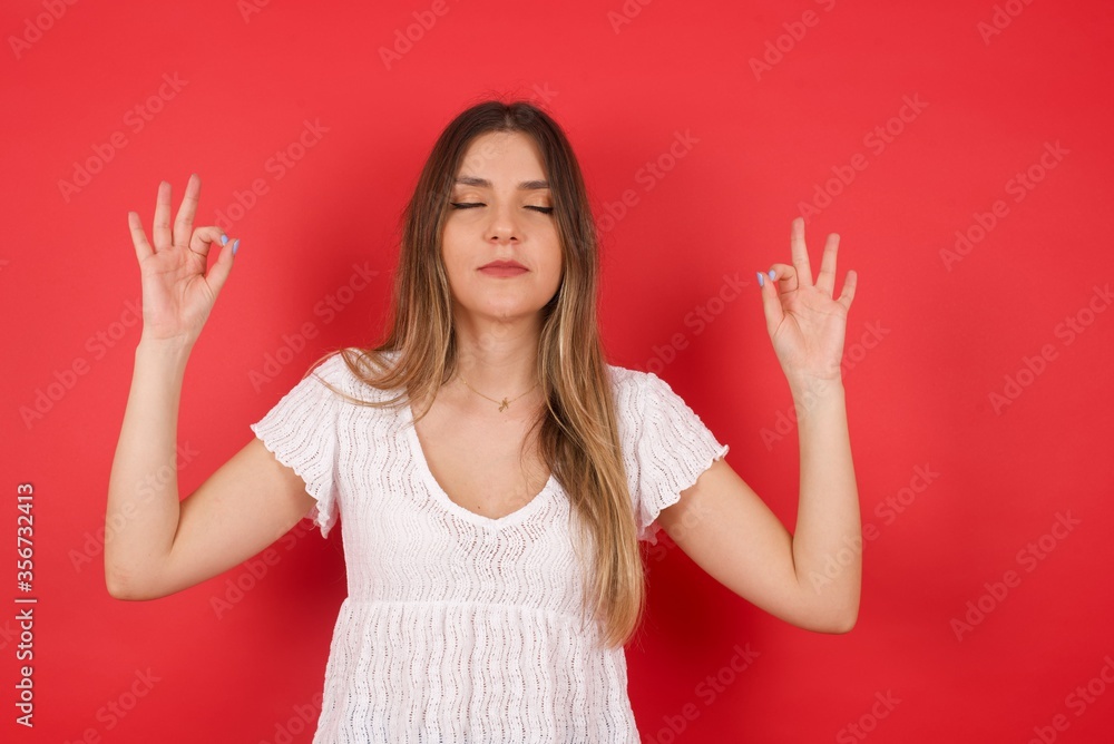 Meditation, religion and spiritual practices. Beautiful young blond haired female doing yoga in the morning outdoors after waking up, keeping eyes closed, holding fingers in mudra gesture. Meditation, religion and spiritual practices. Beautiful young blond haired female doing yoga in the morning outdoors after waking up, keeping eyes closed, holding fingers in mudra gesture.