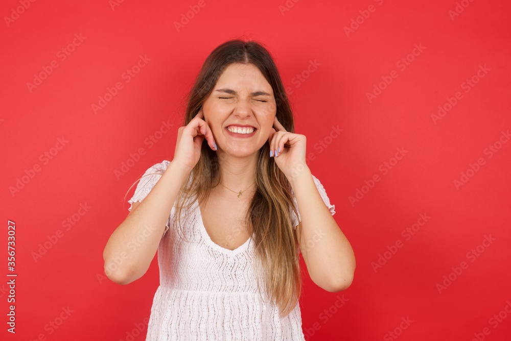 Stop making this annoying sound! Headshot of unhappy stressed out young female making worry face, plugging ears with fingers, irritated with loud noise coming from neighbours who live above her. Stop making this annoying sound! Headshot of unhappy stressed out young female making worry face, plugging ears with fingers, irritated with loud noise coming from neighbours who live above her.