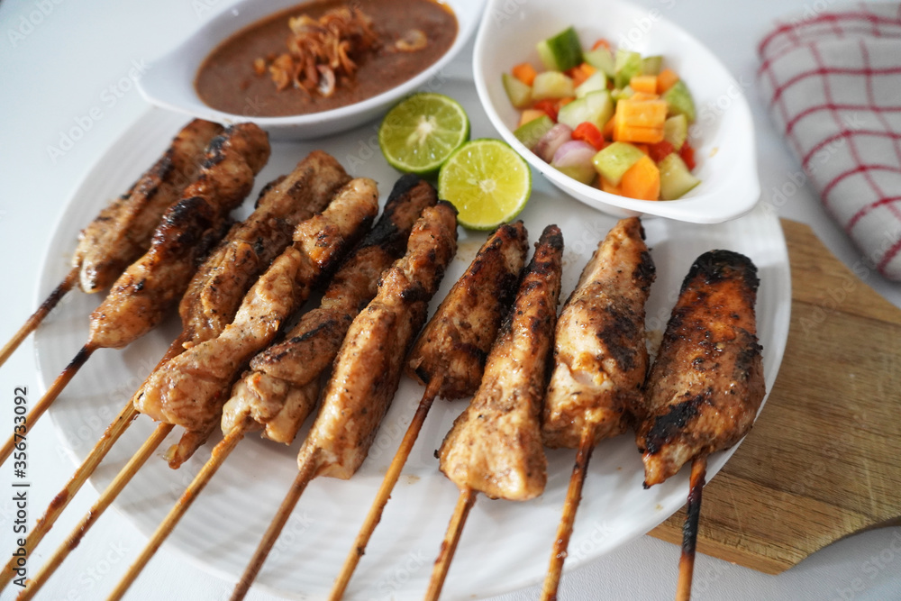 Sate Ayam or Chicken Satay - Indonesian food. Served with peanut sauce and chopped vegetables stock photo Sate Ayam or Chicken Satay - Indonesian food. Served with peanut sauce and chopped vegetables stock photo