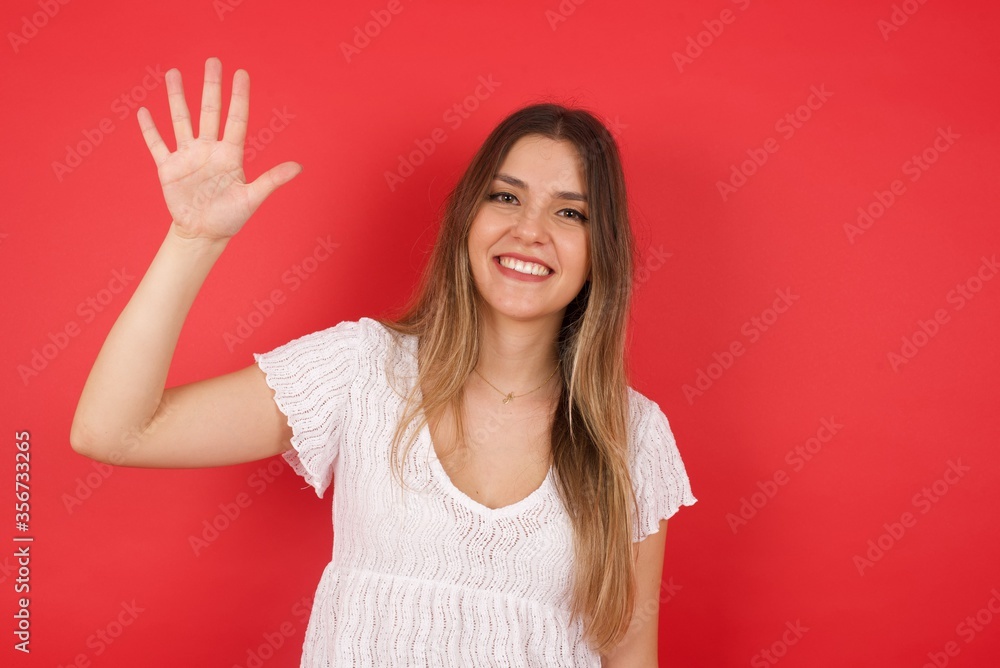 Young woman standing against gray wall showing and pointing up with fingers number five while smiling confident and happy. Young woman standing against gray wall showing and pointing up with fingers number five while smiling confident and happy.
