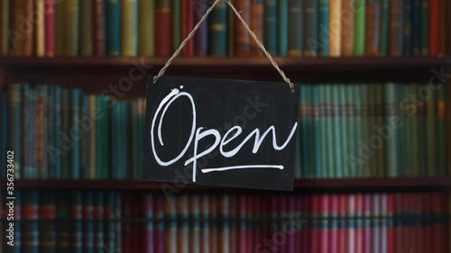 A Swinging Open Sign In The Window Of A Antique Book Store