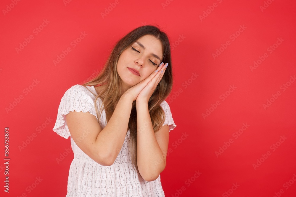 Relax and sleep time. Tired beautiful dark haired girl with closed eyes leaning on palms as pillow pretending sleeping being exhausted seeing dreams standing against gray background. Sleeping gesture. Relax and sleep time. Tired beautiful dark haired girl with closed eyes leaning on palms as pillow pretending sleeping being exhausted seeing dreams standing against gray background. Sleeping gesture.
